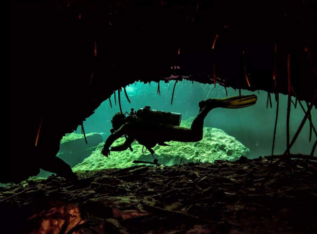 Buceo técnico en cuevas en el Cenote Dos Ojos, México; buceadores siguiendo la línea de vida en un sistema de cavernas cristalinas.